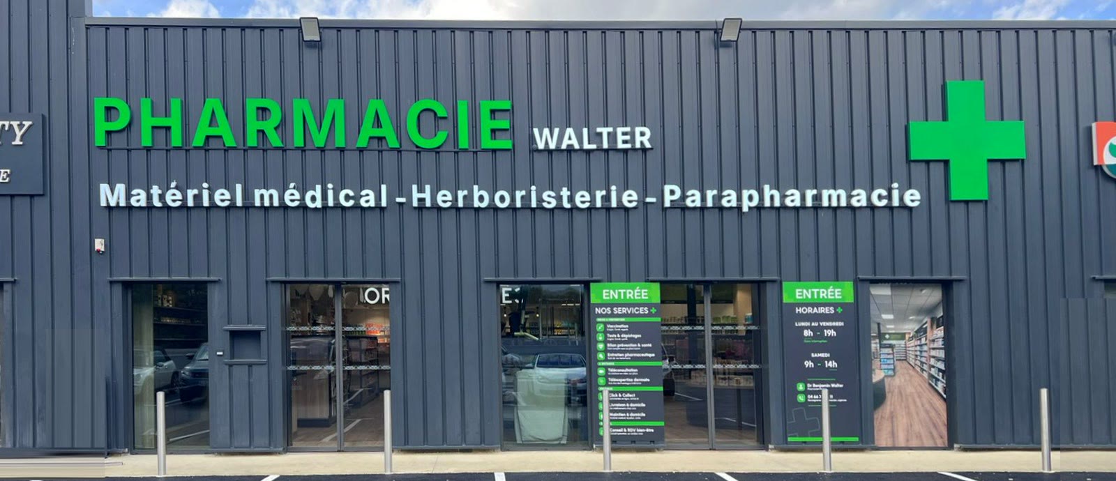 Façade de la Pharmacie Walter, bardage gris anthracite et grande croix verte lumineuse